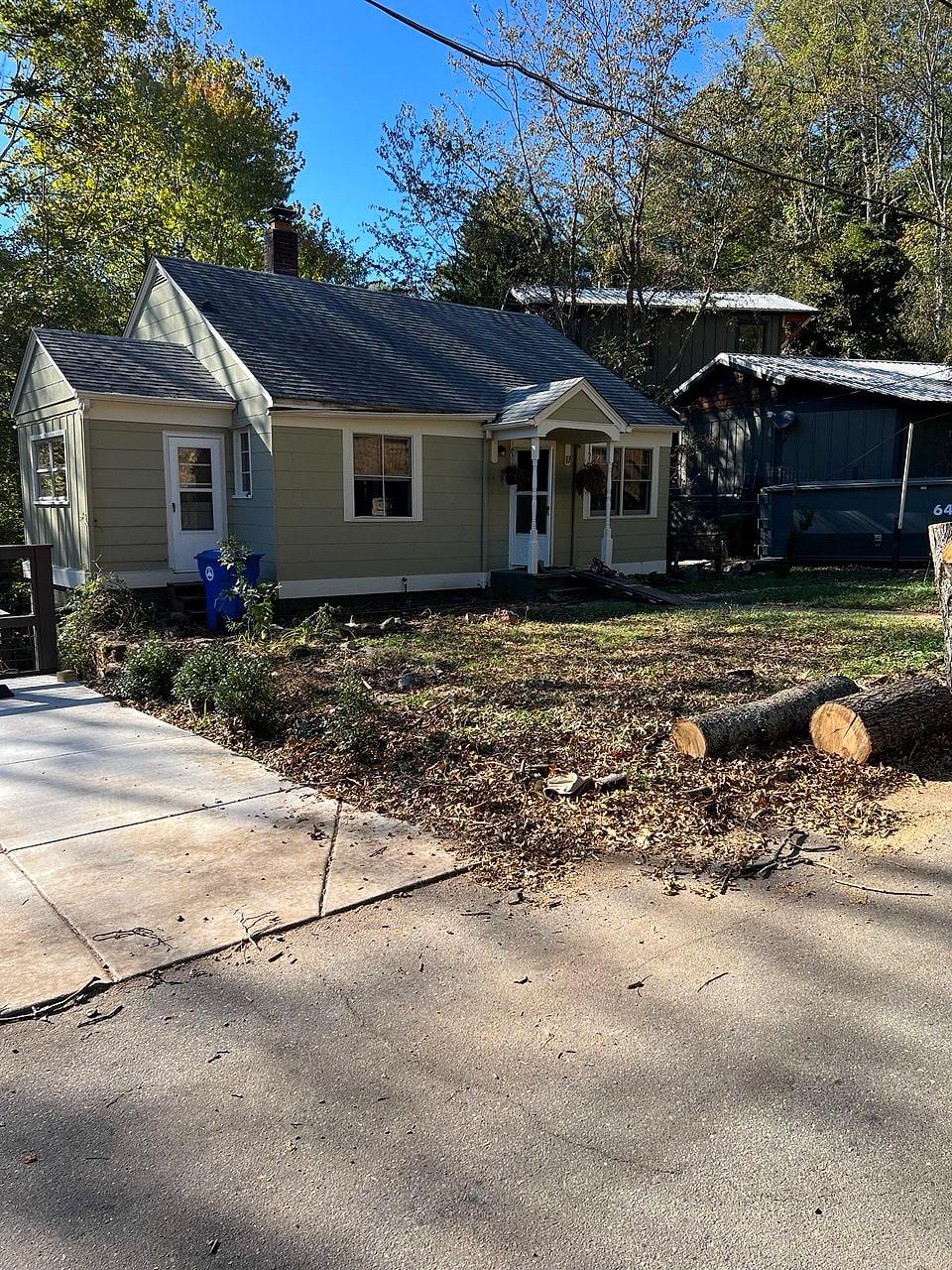 The downtown cottage before renovation — a small tan house behind an overgrown yard