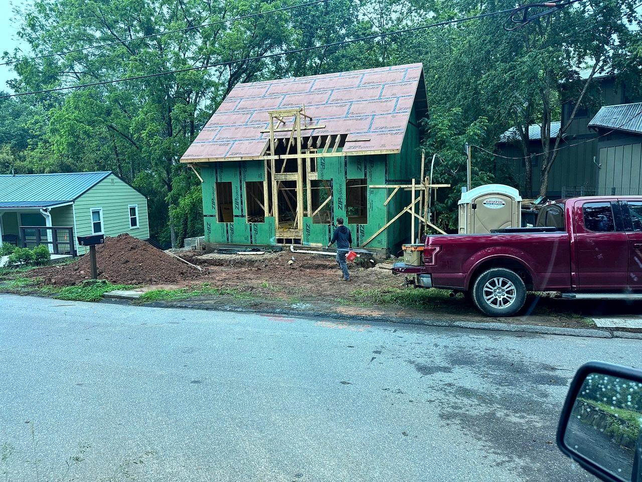 The same cottage mid-renovation — new second-story framing and sheathing going up