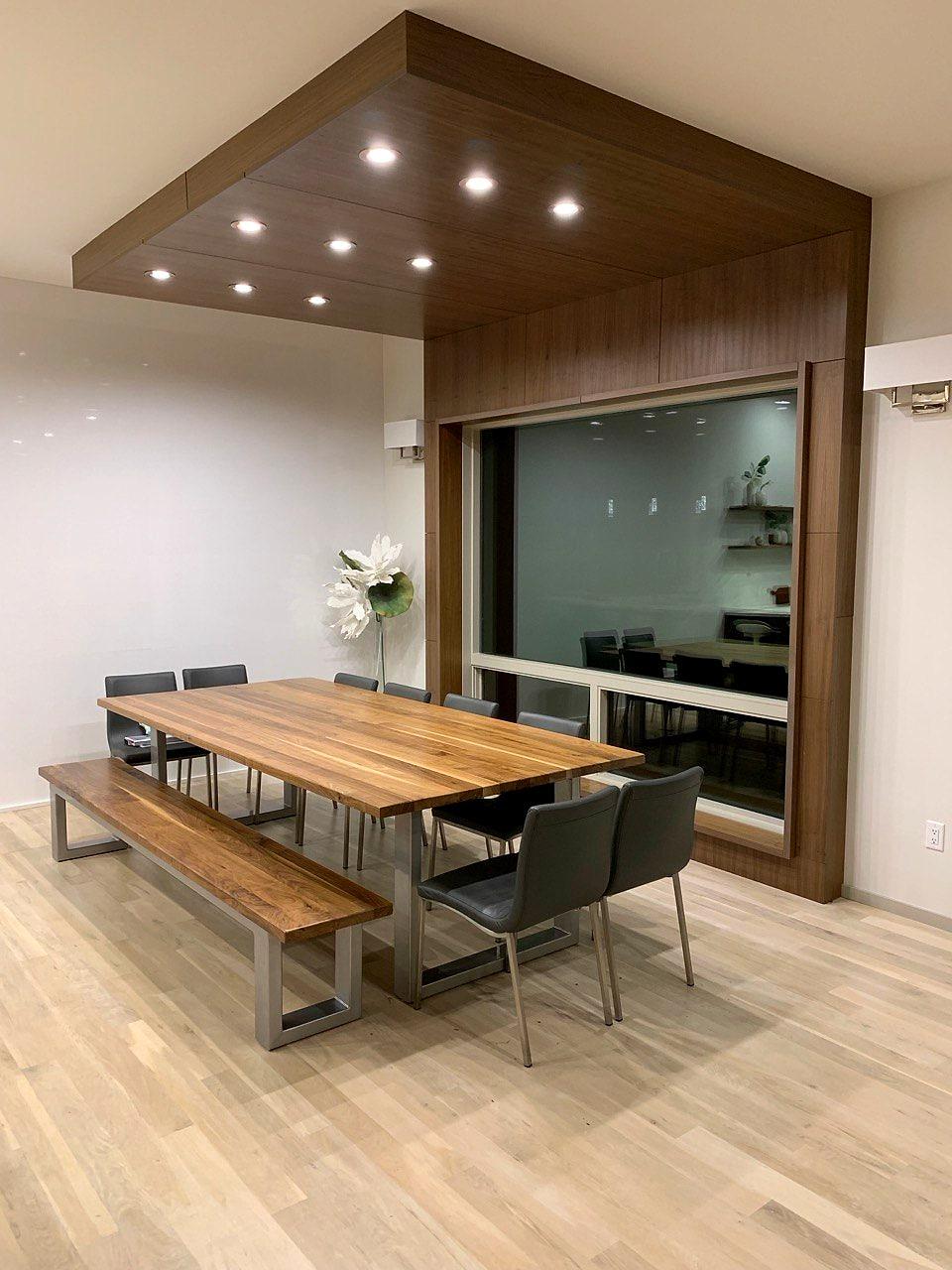 Dining room with a lit wood ceiling feature and a live-edge table