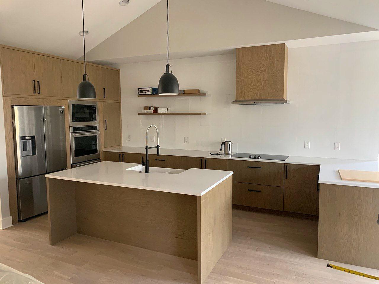 White oak kitchen with an island, black pendants and a matching range hood
