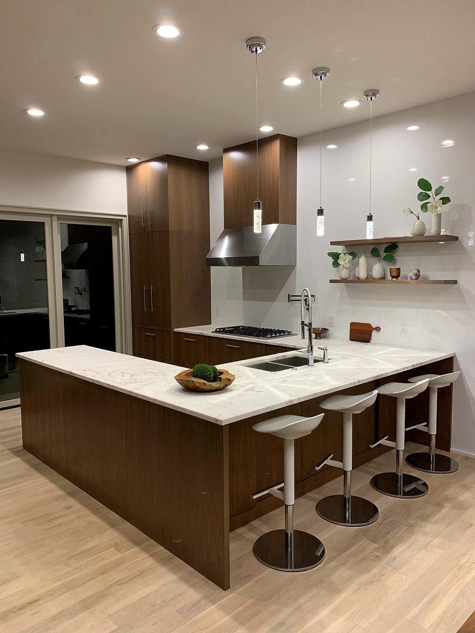 Modern walnut kitchen with a peninsula, floating shelves and glass pendants