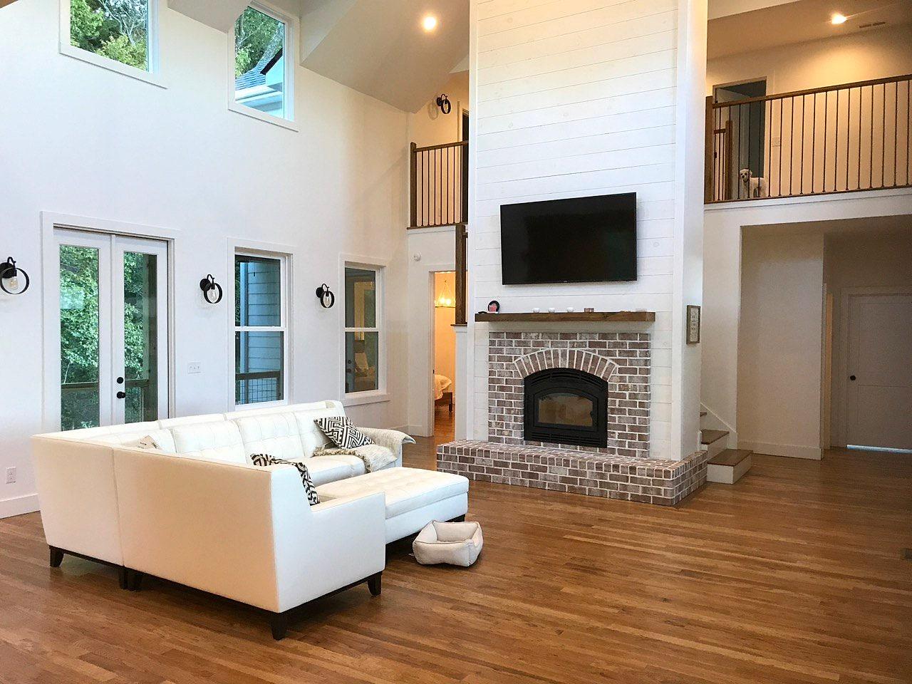 Two-story living room with a brick fireplace and shiplap chimney wall