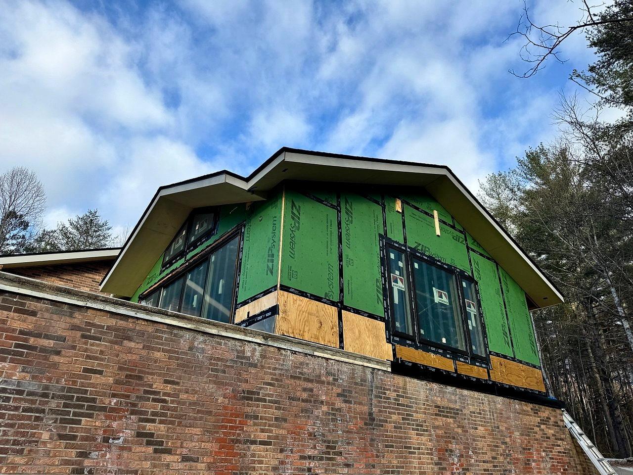 Second-story addition sheathed and wrapped above an existing brick house