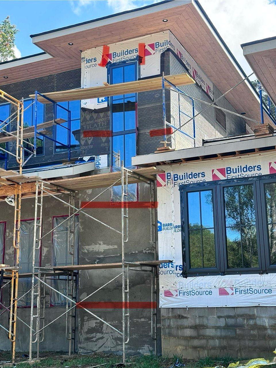 Exterior on scaffolding mid-build, with house wrap and deep roof overhangs