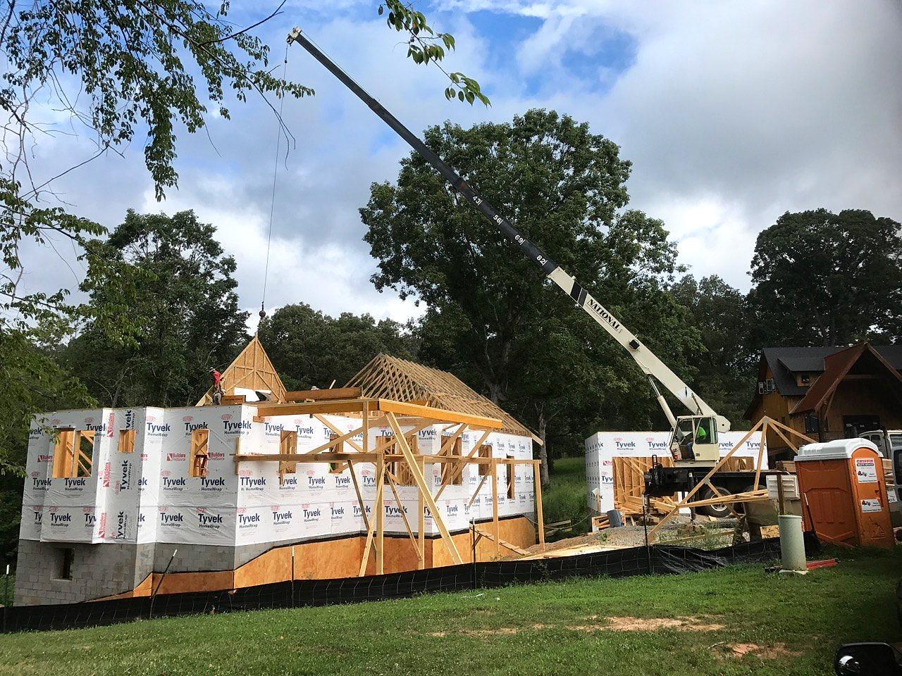 Crane setting roof trusses over the wrapped walls of the Sovereign Oaks home