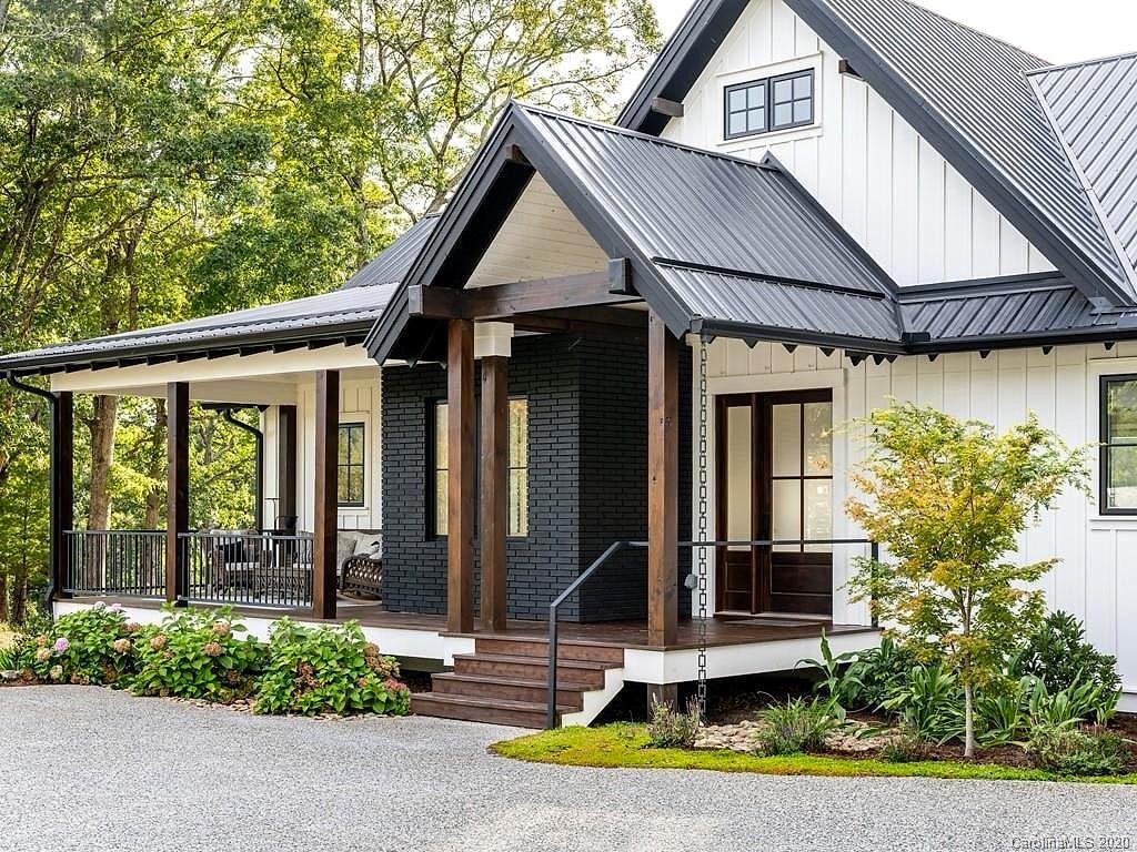 Farmhouse entry with a timber-post gable porch, black metal roof and brick accents