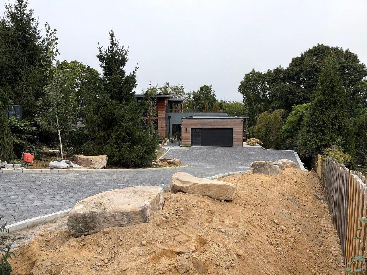 New paver driveway with boulders set along the grade toward the garage