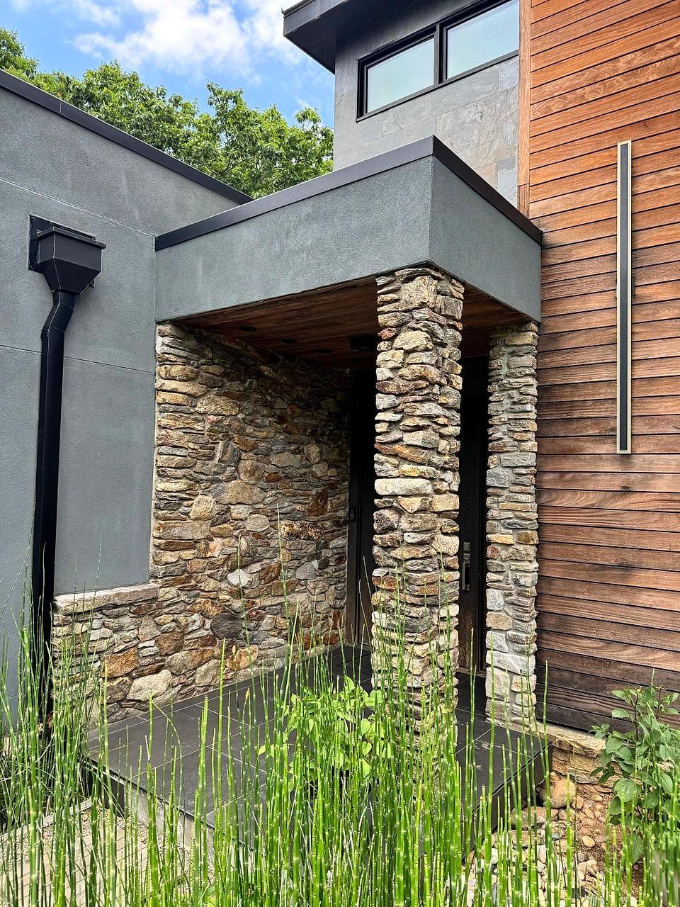 Covered entry with stacked-stone columns, cedar cladding and a steel canopy